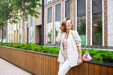 Successful business woman in cityscape background. Stylish lady outdoor with handbag. Fahionable female manager leaves her modern office. Street fashion. ..