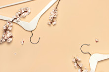 Creative Spring Sale Concept. White Wooden Hangers With Spring Branches Of Apricot Flowers On Beige Background Top View Flat Lay. Fashion Spring Discounts Shopping Sale Store Promo Design Minimalism
