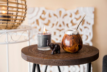 Close Up View Of Yerba Mate Tea Calabash With Metal Bombilla Straw And Elephant Figurine On Small Table In Modern Living Room With Oriental Details.