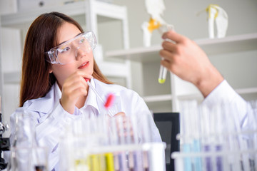 Attractive young Asian scientist woman lab technician assistant analyzing sample in test tube at laboratory. Medical, pharmaceutical and scientific research and development concept.