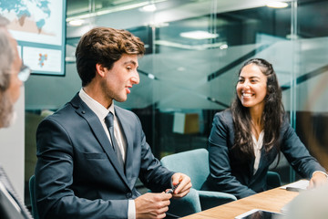 Cheerful business team communicating in conference room. Group of office employees sitting at table and discussing new business plan. Business, teamwork concept