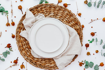 Wall Mural - Table setting mock-up scene. Porcelain plate and cutlery. With flowers and eucalyptus, top view, flat lay. White table background.