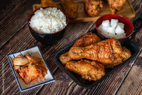 Closed up home made fried chicken with Korean source with garlic, spicy and steamed rice on wooden background, Korean food © Kaojoke