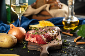 Raw meat on a wooden board with herbs and spices