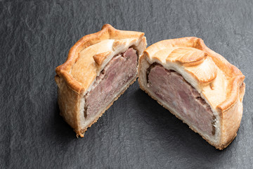 Seasoned cured pork and ham pie on black stone background