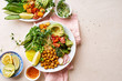 © Anastasiia Nurullina - Healthy vegetarian lunch bowl with avocado, chickpeas, quinoa and vegetables, garnished with microgreens and nut dressing. Flat lay on stone background.