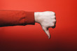 Man hand shows thumb down on red background.
