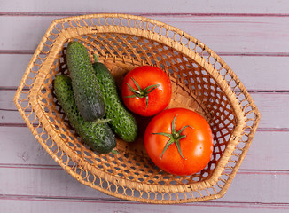 Fresh tomatoes and cucumbers are in the basket.