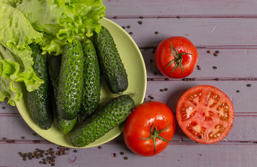 Fresh tomatoes, cucumbers, lettuce and peppers are on the table.