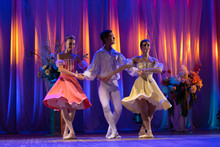 Trio Of Young Girls Ballerinas And A Young Man Dancing Ballet Performance On Stage In The Theater On A Blue Purple Background