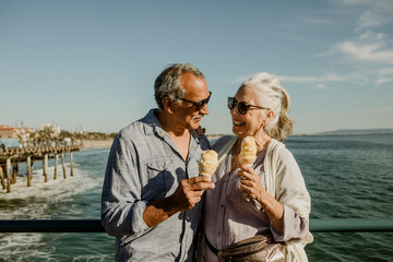 Wall Mural - Happy couple enjoying ice cream by the sea