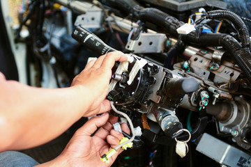 Mechanic are assembling console parts in the front passenger compartment after repairing the air conditioning system in the car. Automotive steering wheel assembly process.