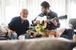 © chokniti - elderly dad and son are playing music at home, relax activity at home with family