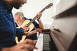 © chokniti - elderly dad and son are playing music at home, relax activity at home with family