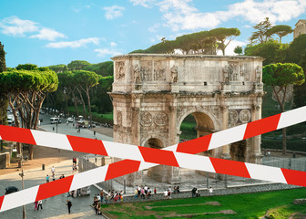 The barrier tape symbolizes quarantine and a ban on entry due to a pandemic. View of the Arc de Triomphe from the Coliseum in Rome, Italy.