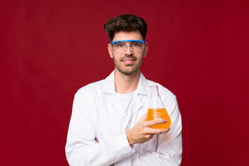 Wall Mural - Young man over isolated background with a scientific test tube