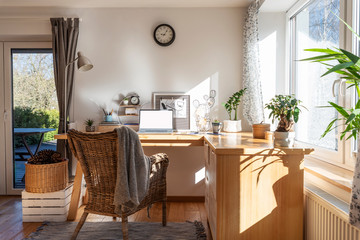 interior of home office with wooden office desk with laptop near big window. light, bright and styli