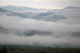 Fototapeta Las - View landscape with silhouettes of mountains range with mist or covered by heavy fog
