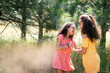 © Inti St. Clair - Sisters playing together outside in summer dresses in forest