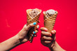 © Inti St. Clair - Two girls hands holding up ice cream cones against bright pink background