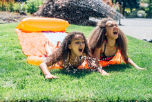 Cheerful Girls Playing On Slip 'n Slide In Backyard