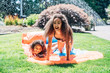 © Inti St. Clair - Girls playing on slip and slide in front yard of home