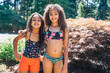 © Inti St. Clair - Portrait of girls swimsuits in front yard hugging and smiling