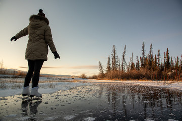 woman skating on frozen lake in wild & isolated yukon territory, northern canada. active, activity, 