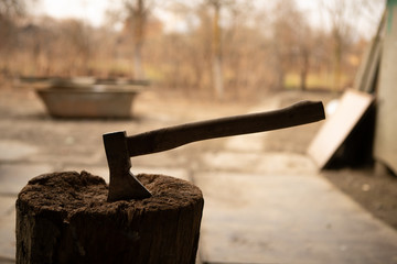 Old rustic ax in wood chopper with wooden blooded handle in rural countryside