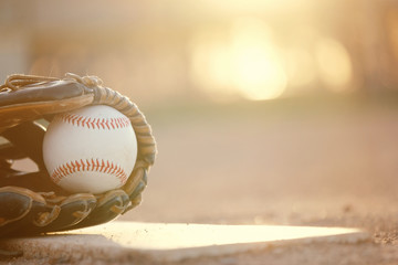 Sticker - Baseball in glove on ball field in park at sunset, blurred background with copy space beside sports equipment.