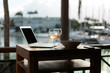 Laptop computer on a wooden table with a blurry marine background