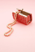 Close-up Of Pearl Necklace And Purse Against Pink Background