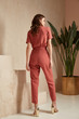 © indiraswork - Beautiful woman fashion model brunette hair tanned skin wear pink red overalls suit sandals high heels accessory bag clothes style journey safari summer collection plant flowerpot wall stairs.