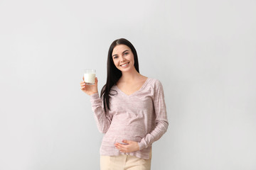 Canvas Print - Beautiful pregnant woman with milk on light background