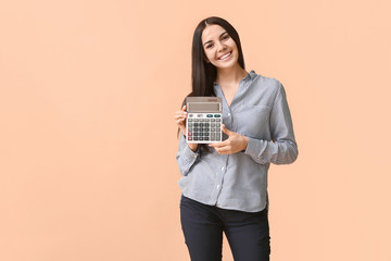 Wall Mural - Young woman with calculator on color background