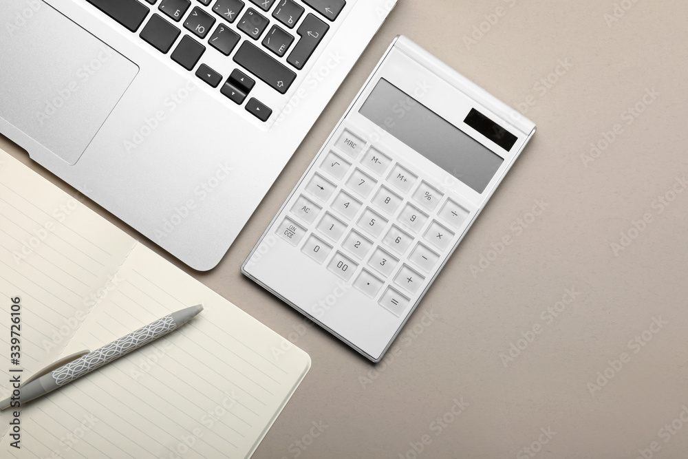 Calculator with stationery and laptop on grey background