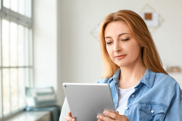 Wall Mural - Mature woman using tablet computer for online learning at home