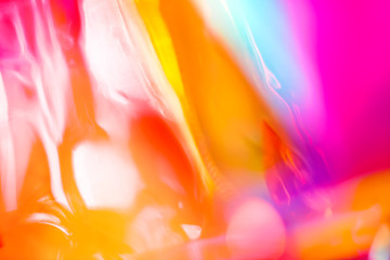 Abstract holographic vibrant party poster background of shiny blurred lens flare lights in vivid glowing spectrum rainbow neon colors