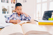 © successphoto - Young student boy makes his exercise sitting at table. Students studying and reading with books in library. Students doing his homework for elementary school. education and back to school concepts.