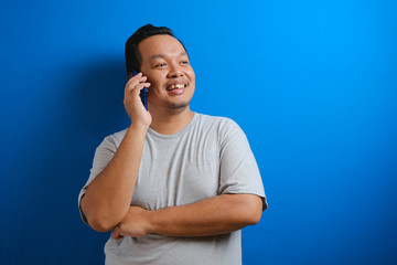 photo of a fat asian man wearing a gray shirt smiling while receiving a phone