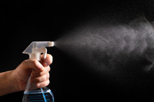 On A Black Background, A Hand With A Spray Bottle. A Spray Of Water. Antibacterial Gel For Hand Disinfection.