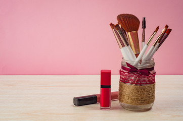 Wall Mural - Make up brushes and lipstick on pink background. Beauty salon concept