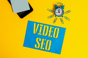 Poster - Handwriting text Video Seo. Conceptual photo the process of improving the ranking or visibility of a video Smartphone metal alarm clock clips paper sheet notepad colored background