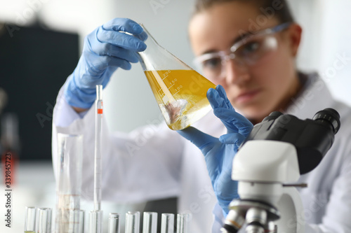 Fotomural Close-up of lab assistant hands holding beaker with oil liquor
