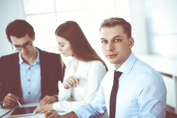 Group of business people discussing questions at meeting in modern office. Headshot of businessman at negotiation. Teamwork, partnership and business concept