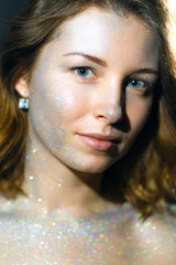 Wall Mural - Portrait of a beautiful girl in a glitter, multicolored sparkling sparkles scattered across her hair and skin.