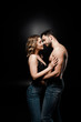 © LIGHTFIELD STUDIOS - side view of sexy shirtless man and beautiful girl in bra hugging on black background