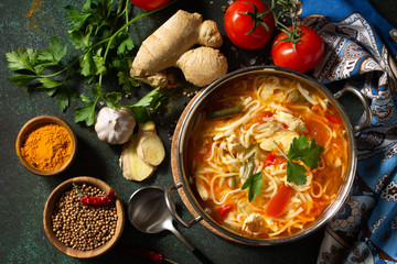 Tukpa soup Indian cuisine. Hot noodle soup with chicken ginger, cilantro and garlic in a bowl on a dark tabletop. Top view flat lay background.