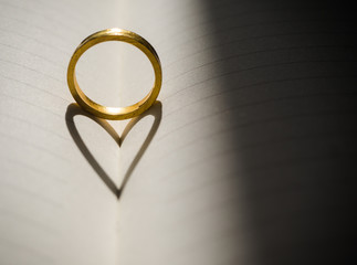 Ring with Heart Shaped Shadow on book background.