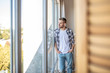 © zinkevych - Young man in a checkered shirt looking out of the window